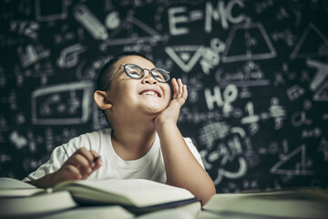 A boy with glasses man writing in the classroom