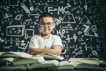 A boy with glasses sitting in the classroom reading
