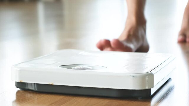 Slow motion video A woman walks in her house and she walks on the scale to Check her body weight on the manual weight scale. Concept of healthy lifestyle and sport