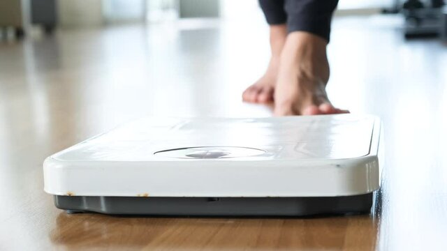 Slow motion video A woman walks in her house and she walks on the scale to Check her body weight on the manual weight scale. Concept of healthy lifestyle and sport
