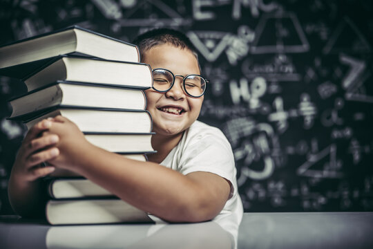 A boy hugging a pile of books.