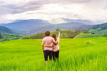 Fototapeta na wymiar Young couple traveler on vacation enjoying and looking at beautiful green rice terraces field in Pa Pong Pieng, Chiangmai Thailand
