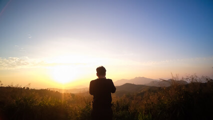 silhouette of young Asian tourist traveler man standing relaxing enjoying beautiful nature morning sunrise at Elephant Hills National Park (Noen Chang Suek) Thong Pha Phum, Kanchanaburi , Thailand