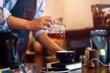 Barista hold drip glass for pouring coffee at coffee shop.
