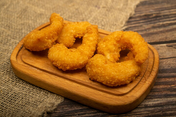 Atlantic prawns fried in batter on a wooden serving Board. Close up.
