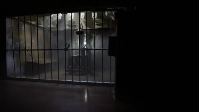 Execution concept. Death penalty electric chair miniature in selective focus inside old prison. Old prison bars cell lock. Creative artwork decoration. Electric chair scale model in the dark