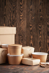 Eco craft paper tableware. Paper cups, dishes, bag, fast food containers, box for delivery food and wooden cutlery on wooden background. Recycling concept. Zero waste.