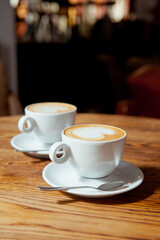 Two white cups of coffee with latte art. Morning in a cafe. 