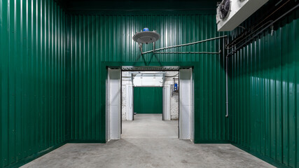 Warehouse interior made of green metal profile with concrete floor and air conditioning, industrial shed or parking lot.
