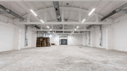 The interior of a huge industrial warehouse made of white bricks with a high ceiling for storing goods. 