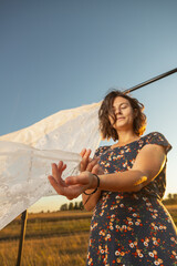 Pretty fresh  young woman  sitting o outdoors in field  and wearing in dress in the background a...