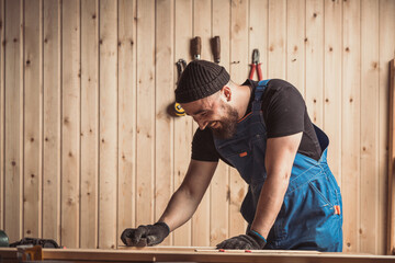 Experienced carpenter in work clothes and small buiness owner working in woodwork workshop,  using...
