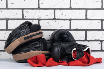 equipment and things for boxing and martial arts lies on a gray floor against a white brick wall