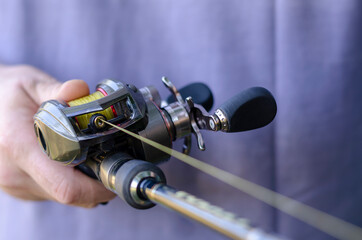 Close-up of male hand with a fishing rod and  baitcasting reel.