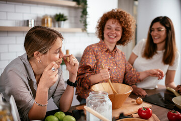 Girlfriends having fun in kitchen. Sisters preparing delicious food at home..