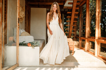 Beautiful brunette girl in a white long dress sundress dances and laughs. The bride is spinning in a wedding dress in boho minimalist style © Yevhenii