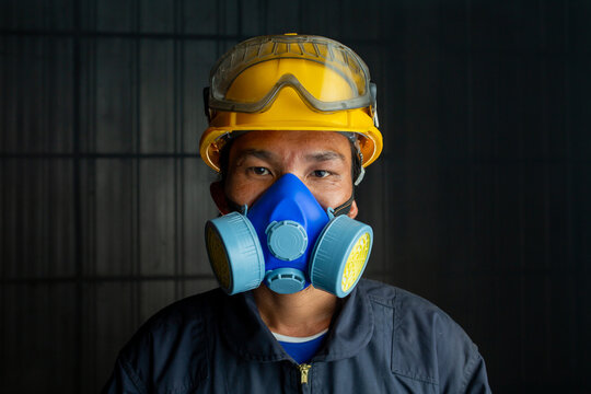 Asian worker wear wears a respirator in a smokey, toxic atmosphere. Image show the importance of protection readiness and safety in industrial factory.