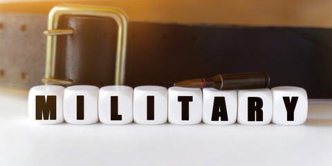 Against the background of a cartridge and a military belt, cubes with the inscription - MILITARY