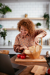 Young woman is reading a recipe while cooking. Beautiful woman with curly hair enjoying in the kitchen.