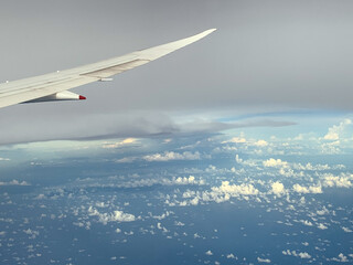 Fototapeta premium Wing of an airplane flying above the ocean. The view from an airplane window.