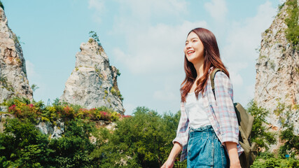 Cheerful young traveler Asian lady with backpack walking at the mountain lake. Korean teen girl enjoy her holidays adventure feeling happy freedom. Lifestyle travel and relax in free time concept.