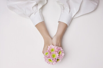 Beauty hands woman with pink flowers in her hands on the table. Natural cosmetic for hand skin care. Hand hydration and anti-wrinkle and anti-aging treatment