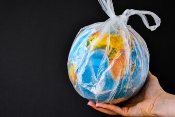ball in the form of a globe is in a plastic bag. concept of plastic pollution of the earth. World...