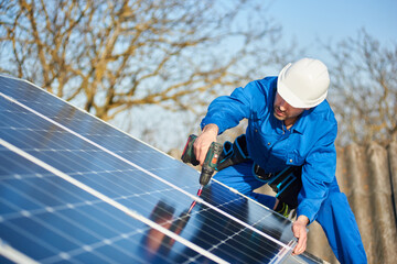 Man worker in blue suit and protective helmet installing solar photovoltaic panel system using...