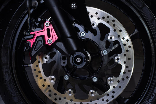 The Front Wheel Of A Motorcycle On A Dark Background. Close-up Disc Brakes And Spokes.