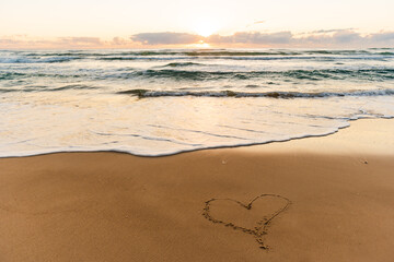 heart on the beach handwriting heart shape on sand coastline ocean with sunrise sunset symbols of love