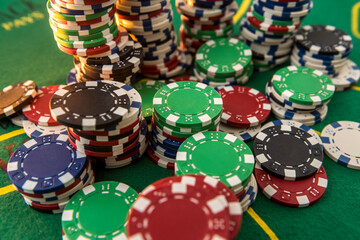Black white red blue green casino chips stacks on green poker table. Betting club and gamble.