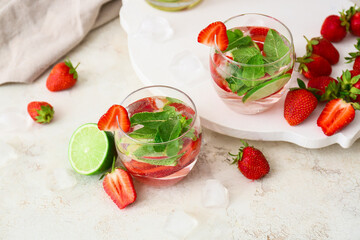 Glasses of tasty strawberry mojito on light background