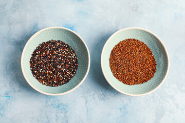 Bowls with different quinoa on color background