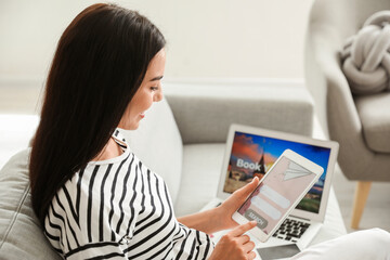 Woman with tablet computer booking tickets online at home