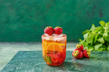 Glass of tasty strawberry mojito on color background