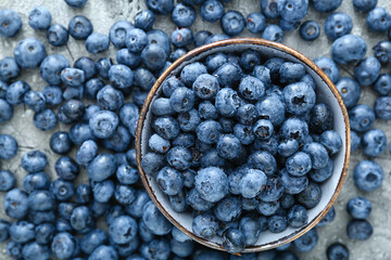 Bowl with tasty blueberry on grey background