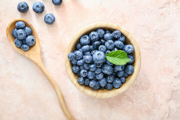 Bowl and spoon with tasty blueberry on light background
