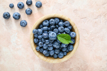 Bowl with tasty blueberry on light background
