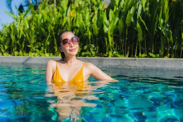 Portrait beautiful young asian woman relax happy smile around outdoor swimming pool in hotel resort