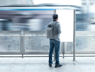 Traveler asian man with backpack looking blank signboard public for information tourism travel in subway train station with copy space for text.