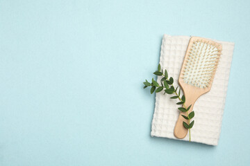Modern paddle hair brush and plant on light background, flat lay. Space for text