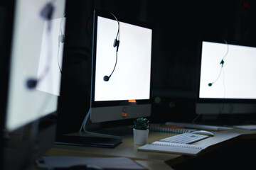 VOIP headset, hands-free phone on desktop computer at call center and customer service help desk at night with bokeh background, work over time