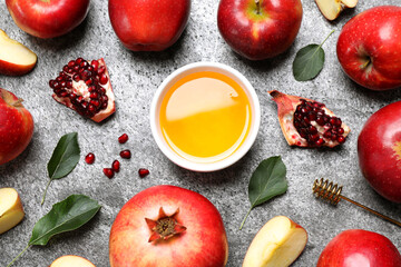 Honey, apples and pomegranates on grey table, flat lay. Rosh Hashanah holiday