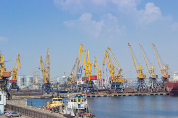 Fototapeta na wymiar Sea cargo port with harbor cranes, sea tugs on foreground