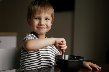 portrait of adorable caucasian boy eating cereal for breakfast. Image with selective focus