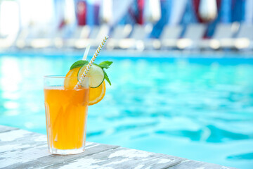 Refreshing cocktail near outdoor swimming pool on sunny day. Space for text