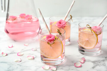 Refreshing drink with lemon and rose on white marble table