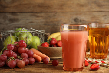 Glasses of delicious juices and fresh ingredients on wooden table