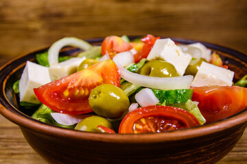 Ceramic plate with greek salad on wooden table