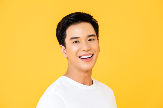 Close Up Portrait Of Young Handsome Asian Man Cheerfuly Smiling And Looking At Camera In Isolated Studio Yellow Background